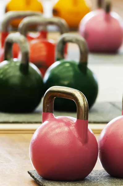 Kettlebells or cast-steel balls with handle of various colors and weights on gym floor