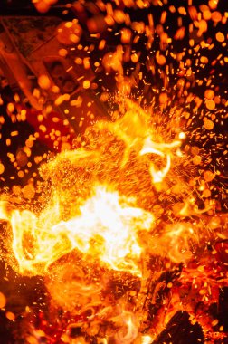 Closeup of explosive scene with chainsaw cutting through burning wood in the dark and sparks flying all over, night shot clipart