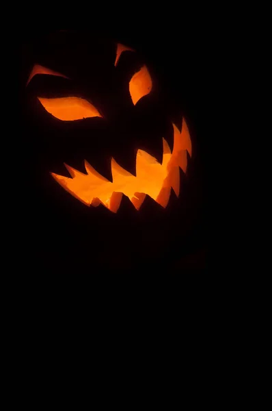 Glowing Jack-o'-lantern Halloween pumpkin with scary glowing face on black background