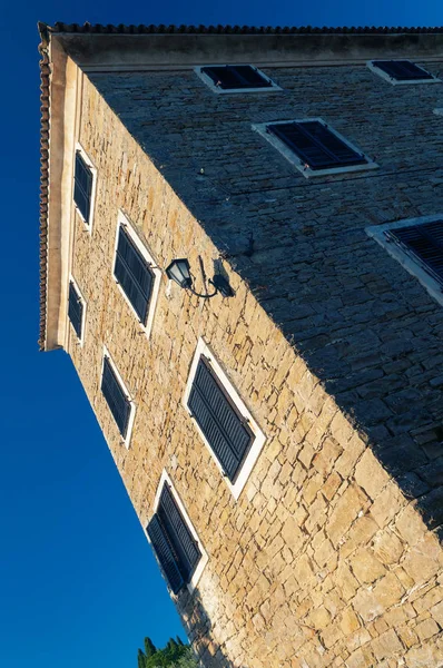 Old istrian house with windows and closed window blinds on deep blue sky in town of Groznjan in Croatia