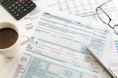 ABD bireysel gelir vergisi beyannamesi 1040 olan form görünür beyaz fincan sade kahve espresso, kalem, hesap makinesi ve beyaz masa gözlük. Vergi, muhasebe, işletme, finans ve office kavramları.