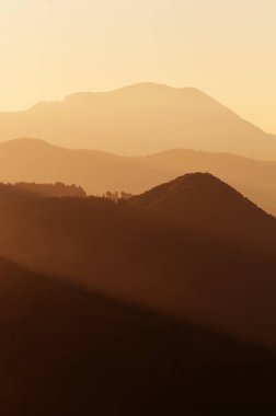 Layers of hills and mountain ranges in beautiful radiant light of setting sun in Slovenia. Tourism, hiking, nature, environment and forestry concepts.