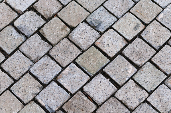 Detail of stone paved ground with cube shaped granite cobblestone. Architecture, history and urbanism concepts.