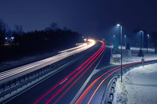 Otoyol gelen ve giden trafiği Ljubljana, Slovenya yakınındaki ışıktan yollar ile gece. Ulaşım, trafik, Şehircilik ve altyapı kavramları.