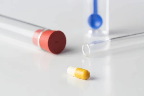 Pill capsule with glass tubes and stool test sampler isolated on white background. Laboratory, antibiotics, medicine, pharmacy and pediatrics concepts.