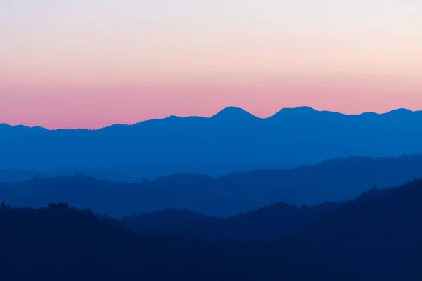 Beautiful pink and blue color nuances of twilight sky and hills after sunset. Travel, hiking, atmosphere, magical nature and environment concepts.