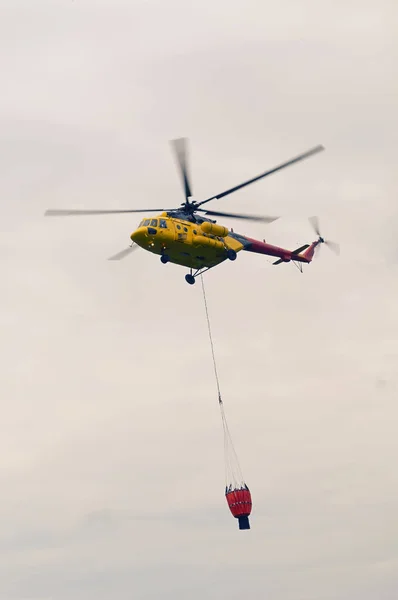 Brand kår helikopter bär en hopfällbar hink för brand släckning — Stockfoto