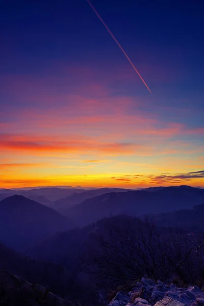 Прекрасне небо і пейзаж після заходу сонця з фіолетовою стежкою від проходження літака — стокове фото