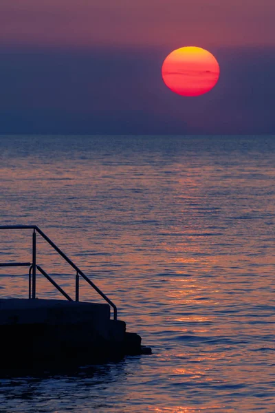 Um velho cais na costa croata e pôr do sol no fundo — Fotografia de Stock