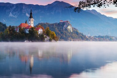 Morning at lake Bled. Church on island with castle and mountains in background clipart