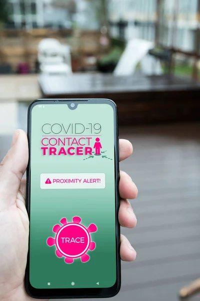 Male hand holding smartphone with Covid-19 contact tracing application mockup. Reducing the spreading of coronavirus after quarantine, detecting infected people.