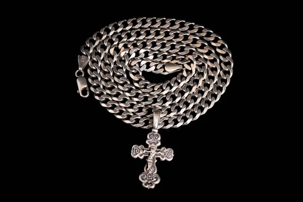 Silbernes orthodoxes Kreuz auf einer silbernen Kette, im Kreis zusammengerollt — Stockfoto