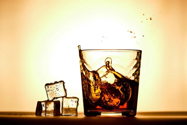 Ледяные кубики рядом со стаканом виски — стоковое фото