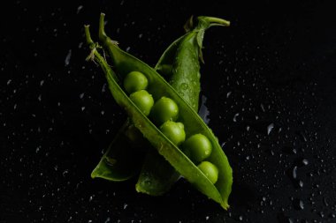 Siyah bir arka plan üzerinde su damlaları taze bezelye yakın çekim