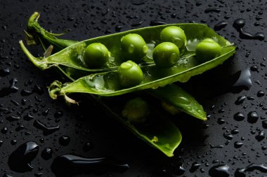 Siyah bir arka plan üzerinde su damlaları taze bezelye yakın çekim