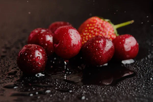 Söta körsbär med jordgubbar i vattendroppar — Stockfoto