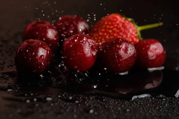 Sweet cherries with strawberries in drops of water — Stock Photo, Image