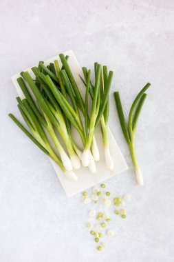 Doğrama Kurulu ve mavi ve mor desenli bir trendy gri DIY arka plan üzerinde taze soğan kesmek bir beyaz mermer üzerinde bir demet taze soğan su ile kulak misafiri atış damla. 