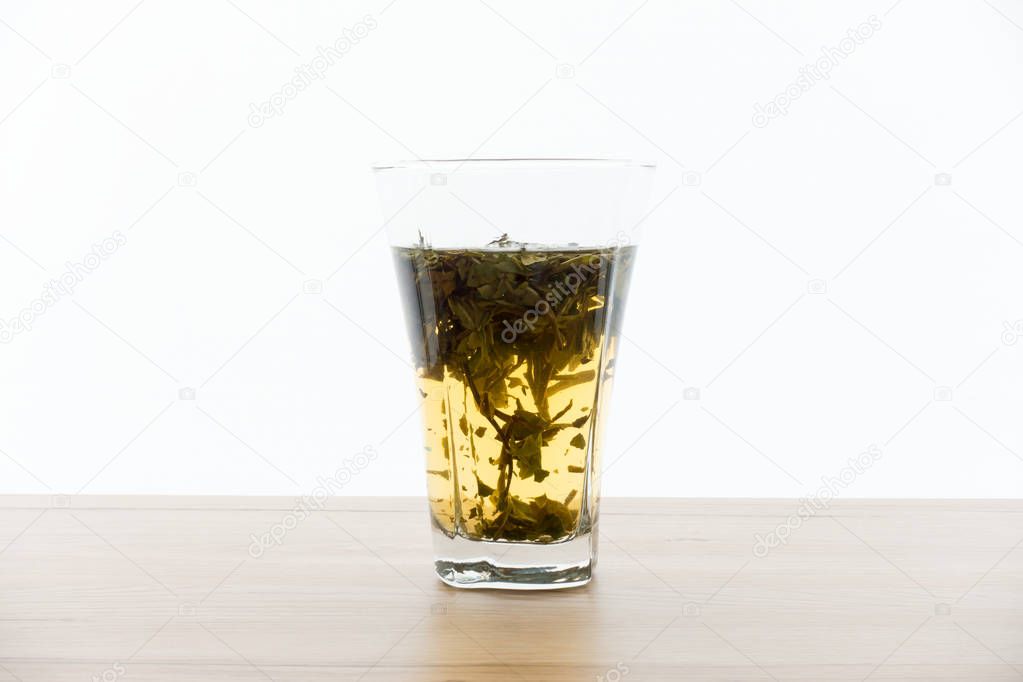 Cold brew white tea concentrate and tea leaves in a highball glass.