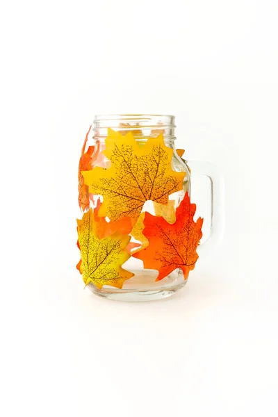 Mason kavanoza tealight ya da mum tutucu ve DIY sonbahar ev dekorasyon olarak yapay sonbahar yaprakları ile dekore edilmiş. 