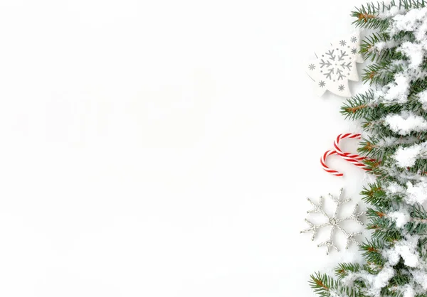Doğal köknar ağacı twigs, beyaz Noel ağacı süsleme, beyaz gümüş Noel yıldız süs ve iki kırmızı ve beyaz çizgili şeker köpekler Noel sınır kar ile kaplı. 