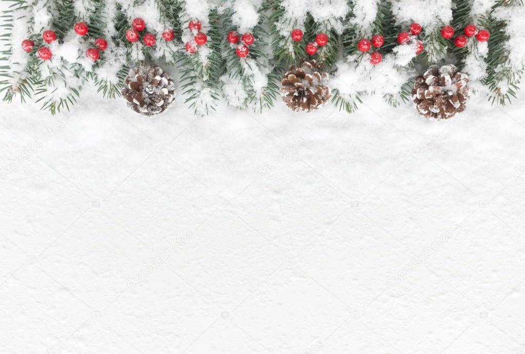 Snow covered Christmas Background with natural fir tree twigs, pine cones and red berries. Top view.