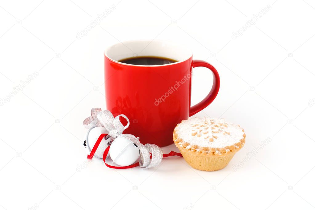 Red mug filled with black coffee ,decorated with white jingle bells, silver metallic ribbon, and a mince pie on white background.