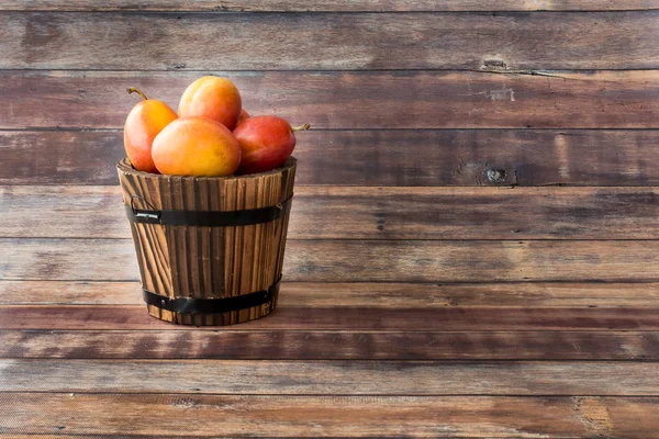 Viktoria Pflaumen im hölzernen Pflanzentopf auf braunem Holzpaneel Hintergrund — Stockfoto