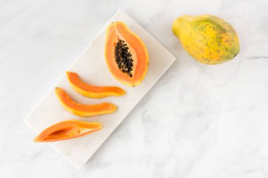 Bütün, yarım ve beyaz mermer Papaya dilimleri