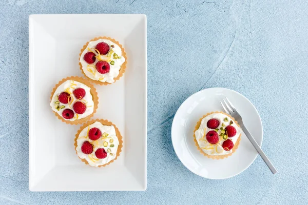 Tartelettes framboises sur assiettes et fond de béton bleu — Photo