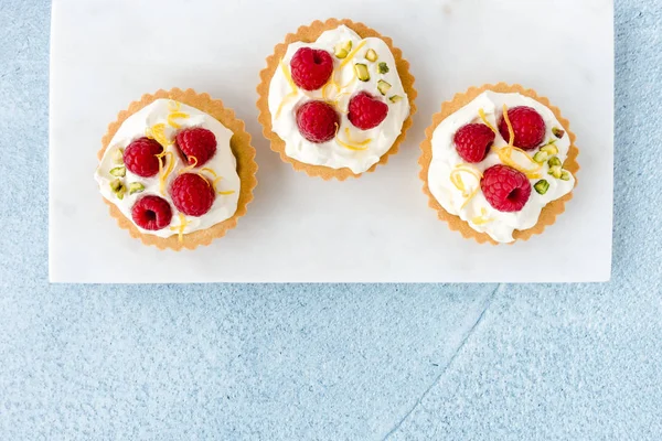 Beyaz Mermer Tahta ve Mavi Arka Plan üzerinde Ahududu Tartlets