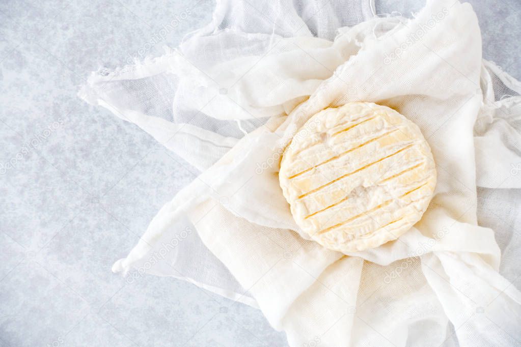 Small Round Soft Cow Cheese on Muslin Cloth and Blue Background