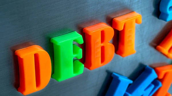 Close up magnetic alphabet scrabble arranged in a word DEBT — Stock Photo, Image