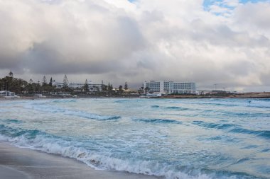 Yaz günü bulutlu yağmurlu bir havada ünlü Kıbrıs Rum Kesimi plajı Nissi 'yi boşalt.