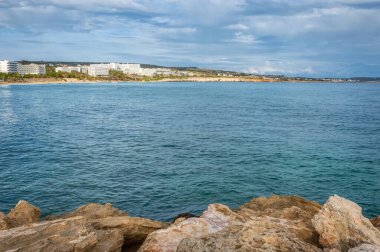Yazın azgın bir denizin arka planında bir kayanın üzerinde duran bir adamın silüeti.
