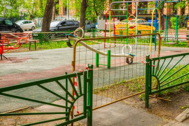 Oyun parkının girişi metal bir şebeke tarafından kapatılmış. Oyun alanı, karantina sırasında kullanılmasını yasaklayan kırmızı-beyaz sinyal bandıyla bağlı. Moskova, Rusya-Nisan 2020