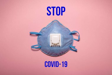 Yazıtlı koruyucu maske koronavirüsü durdurur. Pembe arka planda bir koronavirüs salgınına karşı koruyucu maske. Coronavirüsü durdurmak için yazıtlar..