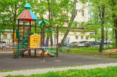 Oyun parkının girişi metal bir şebeke tarafından kapatılmış. Oyun alanı, karantina sırasında kullanılmasını yasaklayan kırmızı-beyaz sinyal bandıyla bağlı. Moskova, Rusya-Nisan 2020