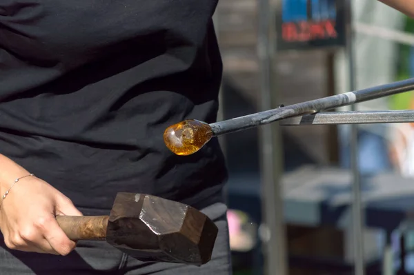 The work of a glassblower craftsman. Hand close up holding a glass blowing tube