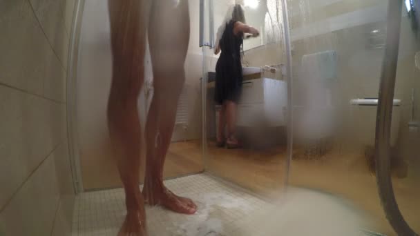 男はシャワー シャワー中下から見られる 鏡の前で自分自身を梳く女たち変色とウェットの窓からご覧下 — ストック動画