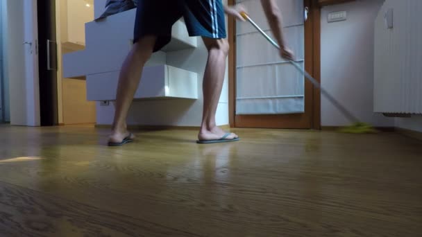 男子穿着翻转拖鞋 洗实木复合地板在卧室与黄色拖把 — 图库视频影像
