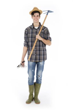 Genç çiftçi makası ve elinde çapa ile o bir hasır şapka, ekose desenli gömlek ve yeşil lastik çizme giyiyor