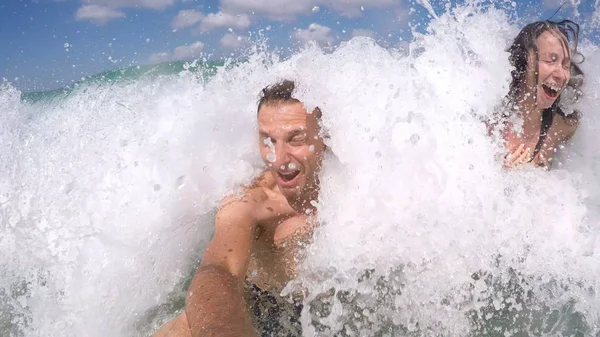 Couple plays amused in the waves at sea