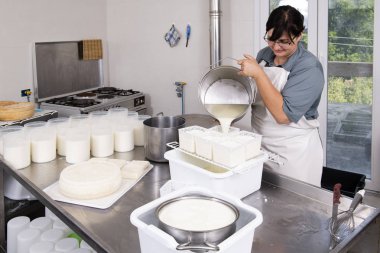 Cheesemaker plastik formları içine lor süt döker