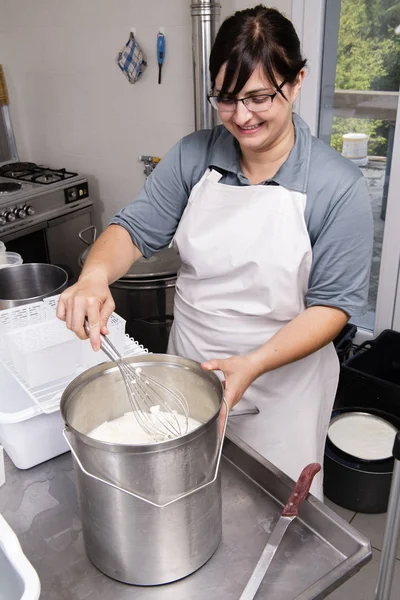 Cheesemaker miesza mleko zkurowane z trzepaczka — Zdjęcie stockowe