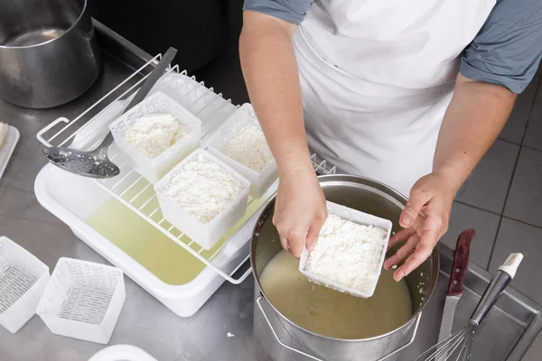 Kaasmaker giet de gekruld melk in de plastic vormen — Stockfoto