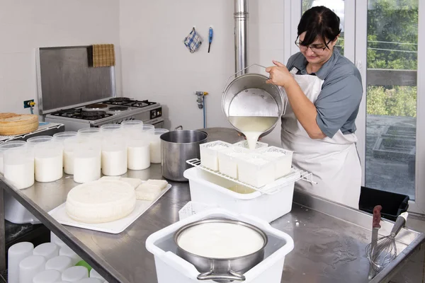 Cheesemaker wylewa mleko zkurowane do plastikowych form — Zdjęcie stockowe