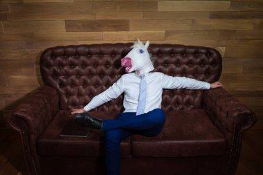 Takım elbiseyle komik tek boynuzlu at kanepe bir patron gibi oturur. Sıradışı adam evde istirahat
