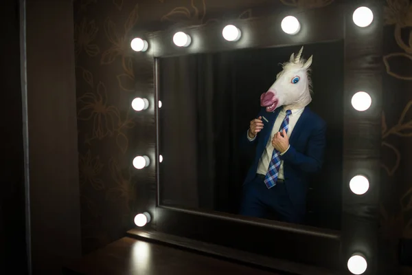 Glamour guy in elegant suit and comical mask looks at himself in the mirror — Stock Photo, Image