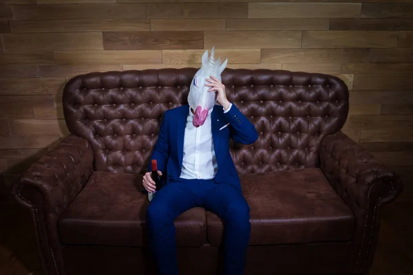 Divertente unicorno in abito elegante si siede sul divano con bottiglia di vino — Foto Stock